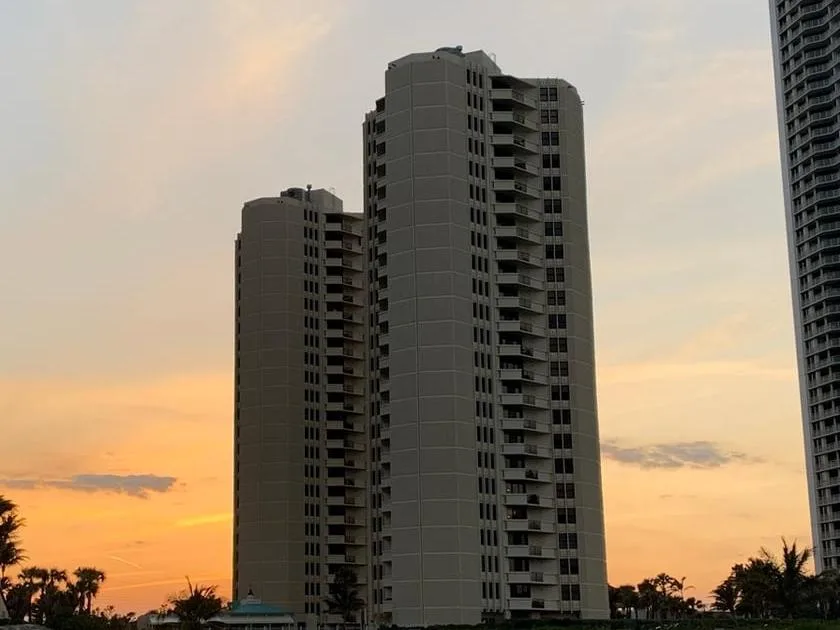 The two tan Phoenix Towers buildings seen from the beach at sunset