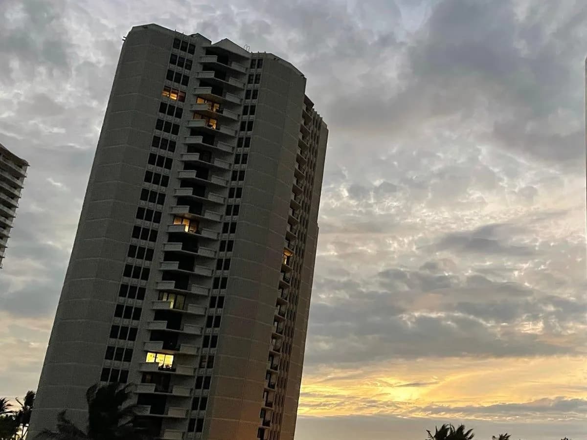 A Phoenix Towers building at dusk under a cloudy sky, a few windows lit
