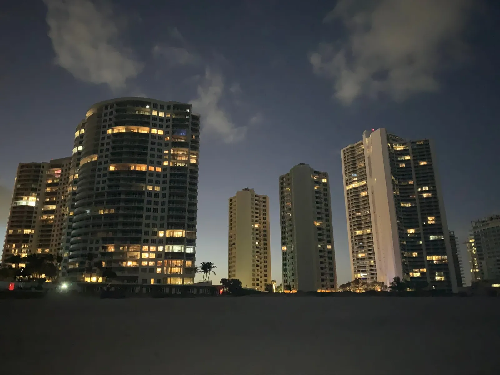 Lit oceanfront towers at night seen from the beach, the Ritz-Carlton Singer Island at left
