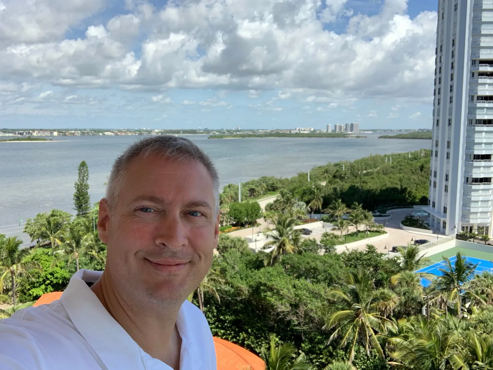 John Oliver of DO Homes Group on a Via Delfino balcony, with the Lake Worth Lagoon behind him